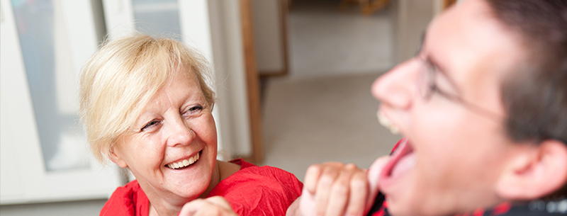 Woman sitting and smiling at a young man in a wheelchair