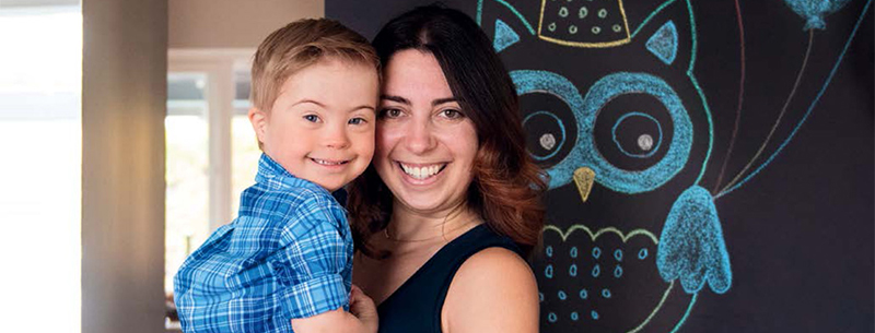 Mother holds young boy in her arms as they both smile