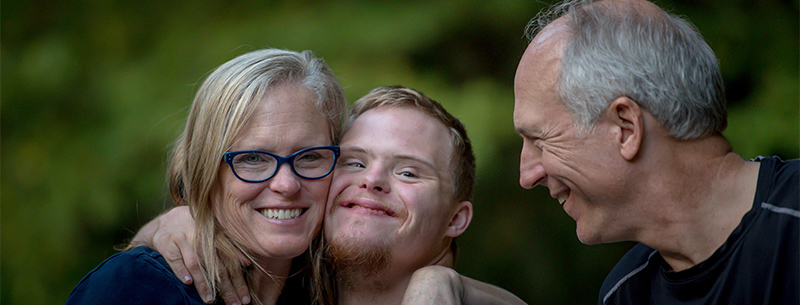 mother hugs son while father watches and smiles