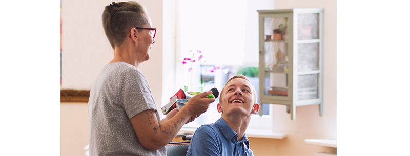 Woman is feeding a young man in a wheelchair