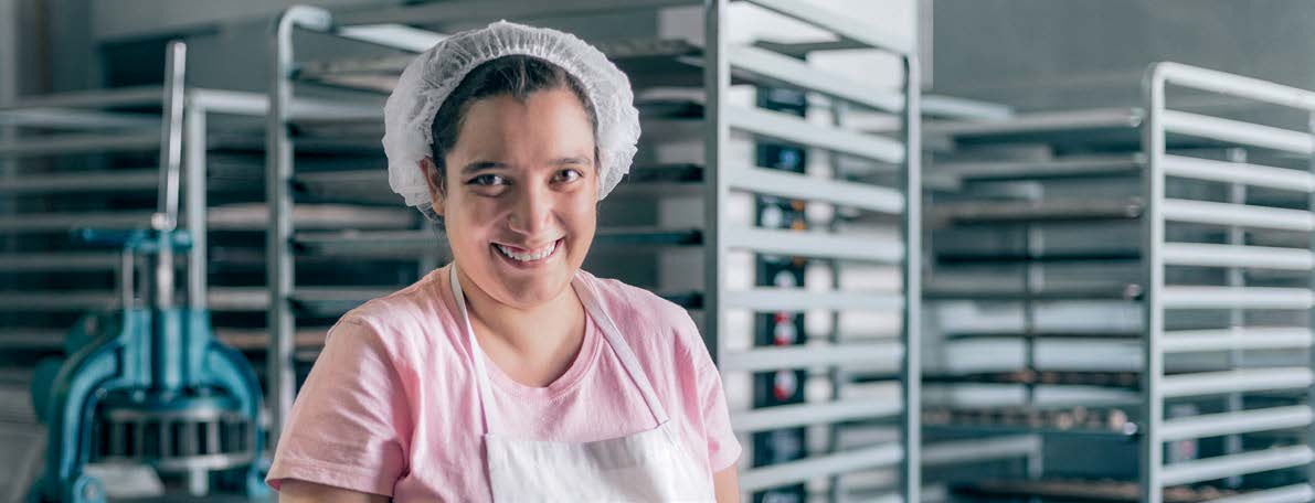 Woman in a bakery with a tray of biscuits smiling