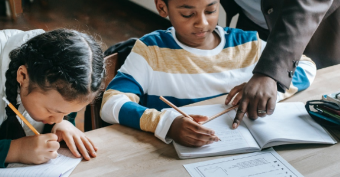 A boy and a girl are sitting at a desk doing school work.