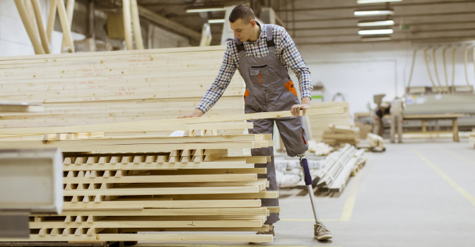Man with artificial limb is working in a furniture building factory.