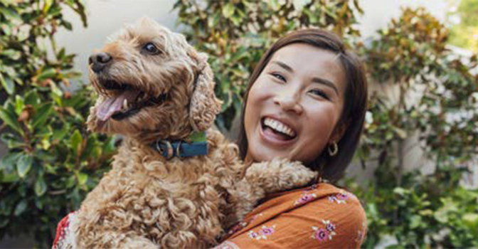 Woman smiling holding a happy dog.