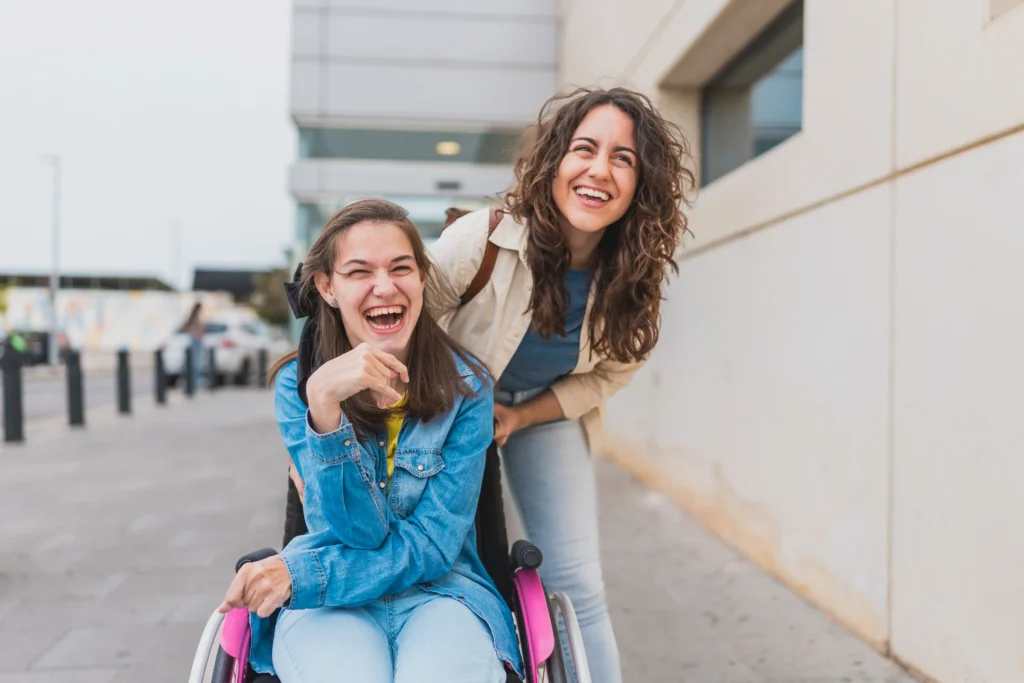 Young woman sitting on wheelchair outdoors with her support worker.