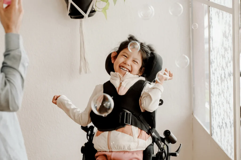 Young girl in a wheelchair laughing with bubbles in the air