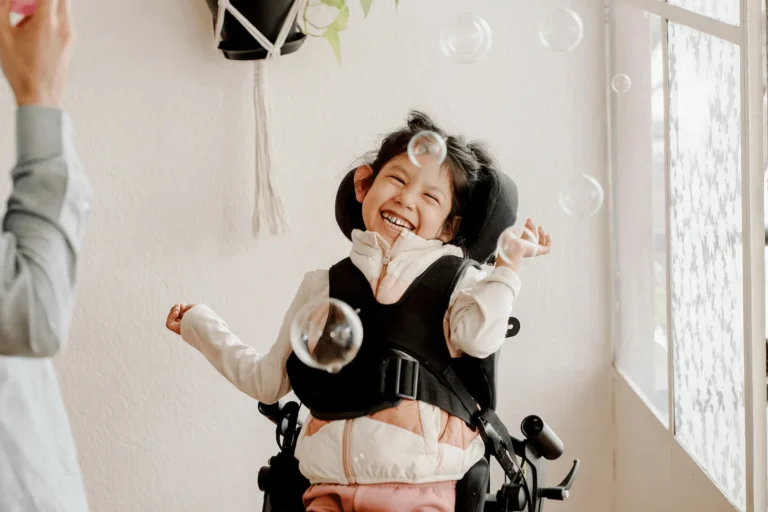 Young girl in a wheelchair laughing with bubbles in the air