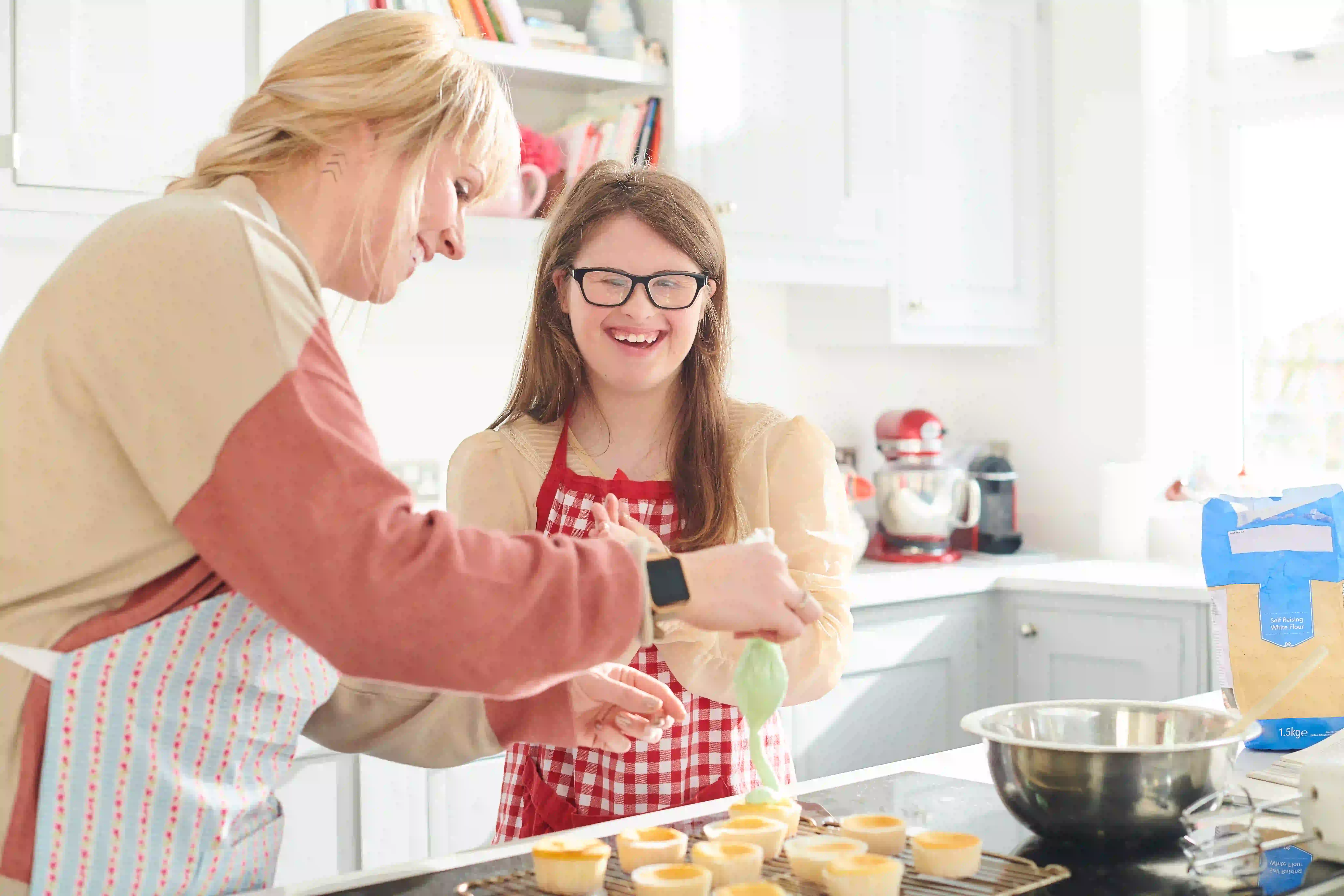 Young woman learning to cook with support in a bright kitchen.