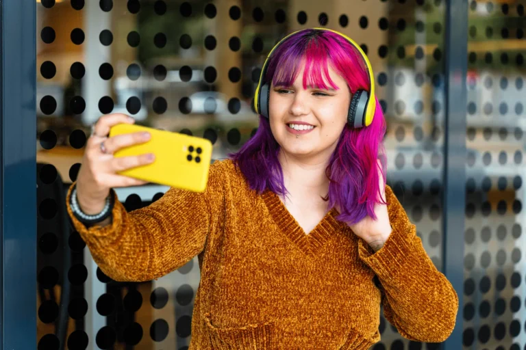 A teenager with headphones on looking at a smartphone