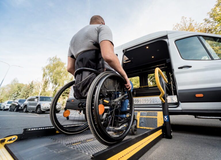 A man in a wheelchair on a ramp getting into a modified car