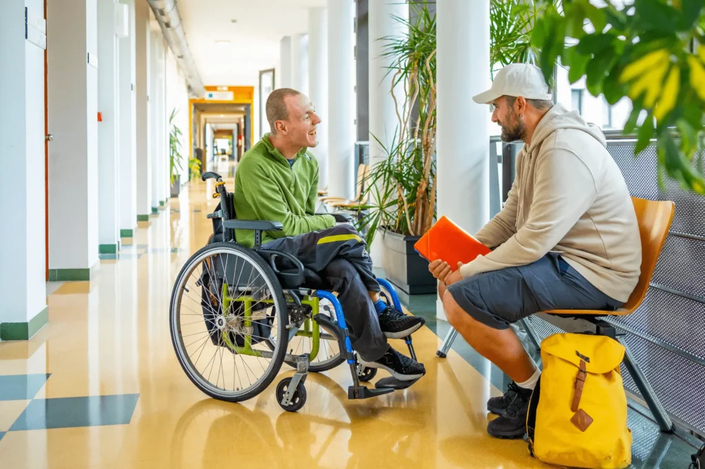 A young man in a wheelchair with his support worker at university