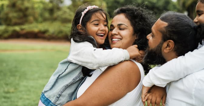 Mother holding daughter in her arms, both smiling