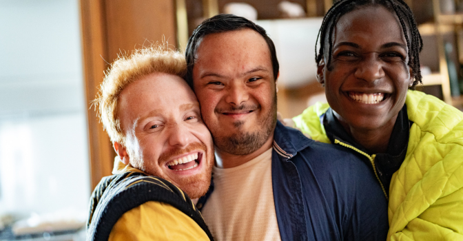 A young man with his arm around his support worker, both smiling