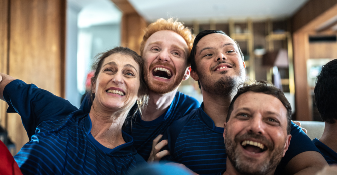 A group of young adult friends with their arms around each other, smiling