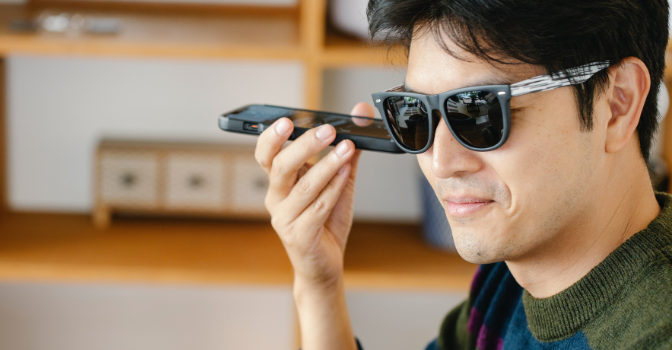 A man with sunglasses on is listening to a mobile phone