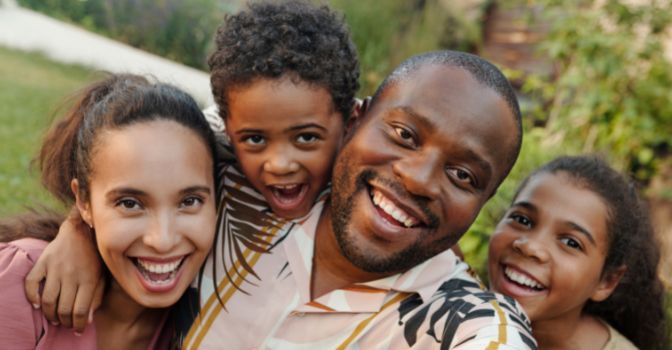 A young family wth their arms around each other, smiling