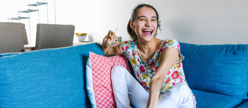 Young woman laughing, sitting on a couch