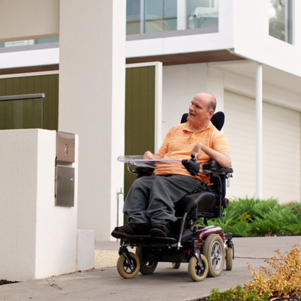 A man in an electric wheelchair outside a residential unit complex