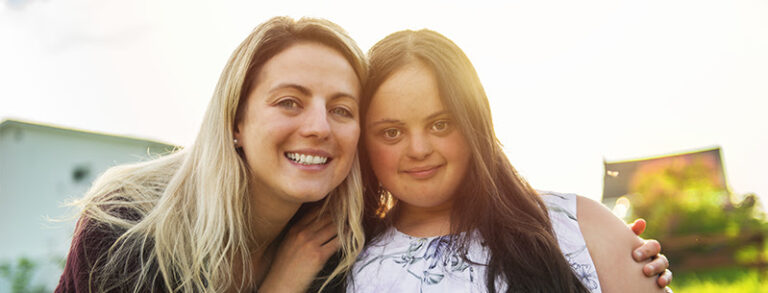 Support worker with her arm around a young woman.