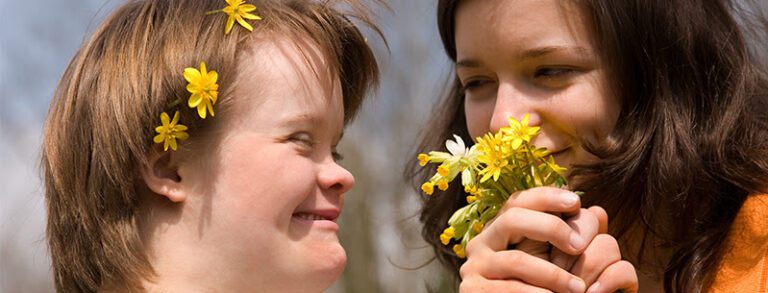 Two young women arelooking at a flower
