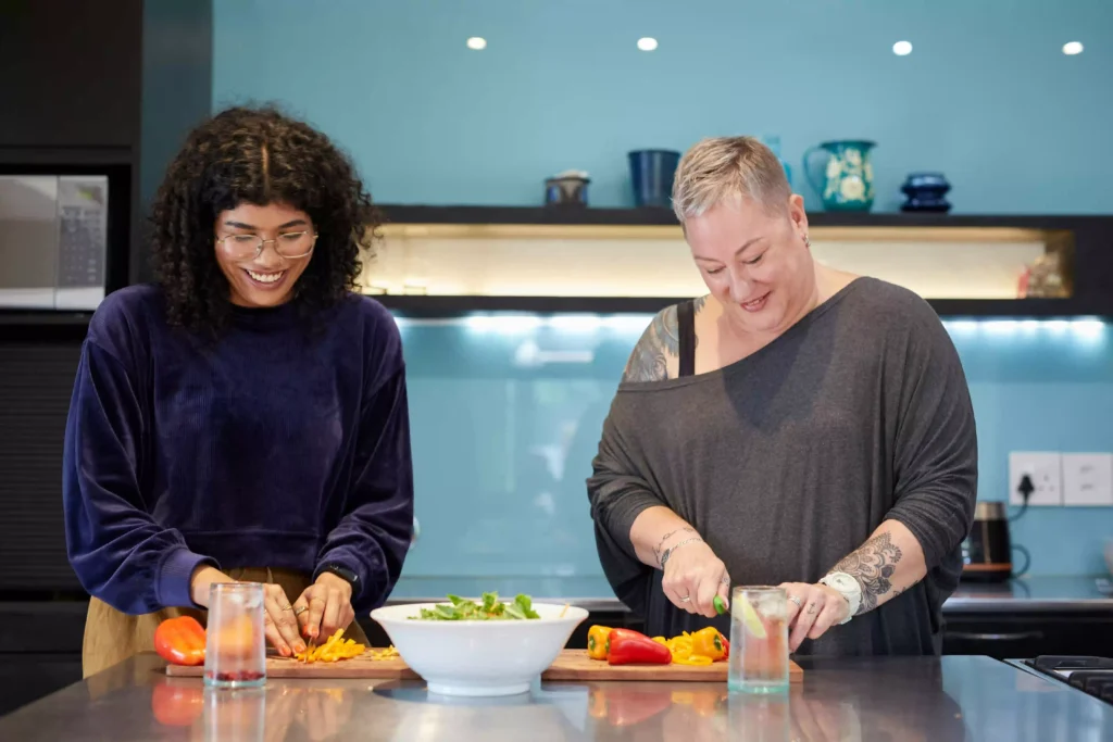 two women chopping vegetables in the kitchen as they prepare a meal