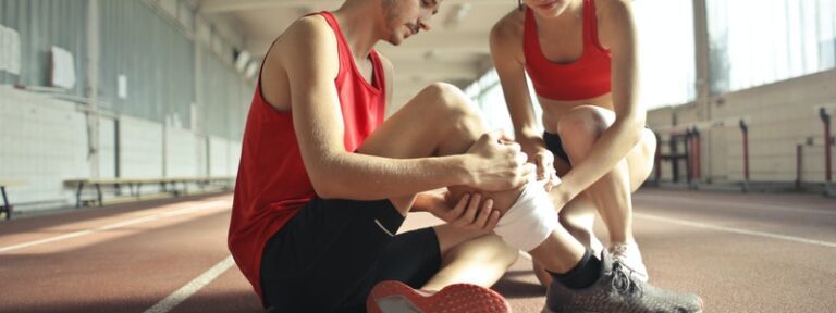 A young man with leg injury is talking with a woman on a sports training track