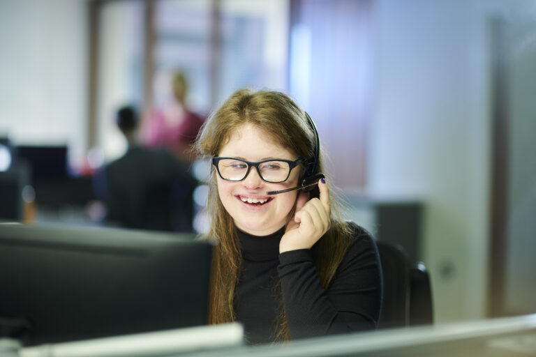 Young woman with a headset on sitting at a desk in an office setting