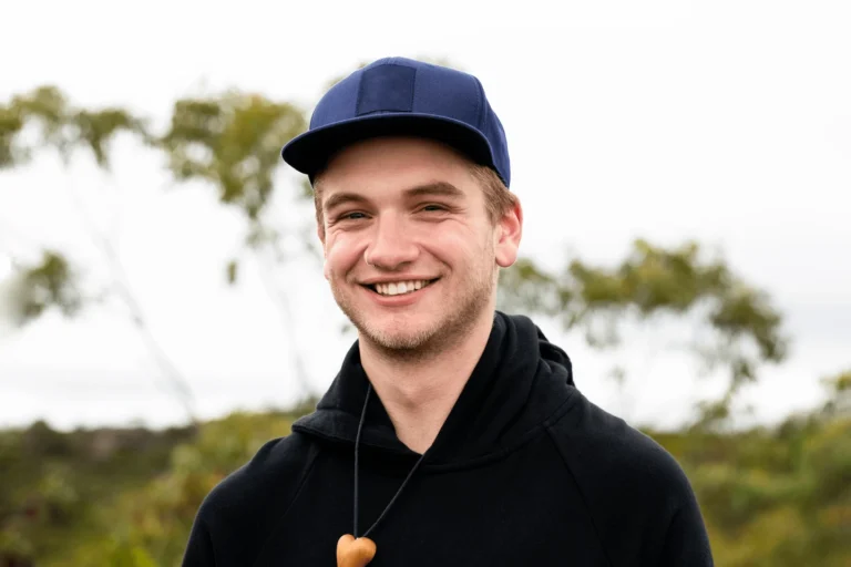 A young man with a cap on, smiling