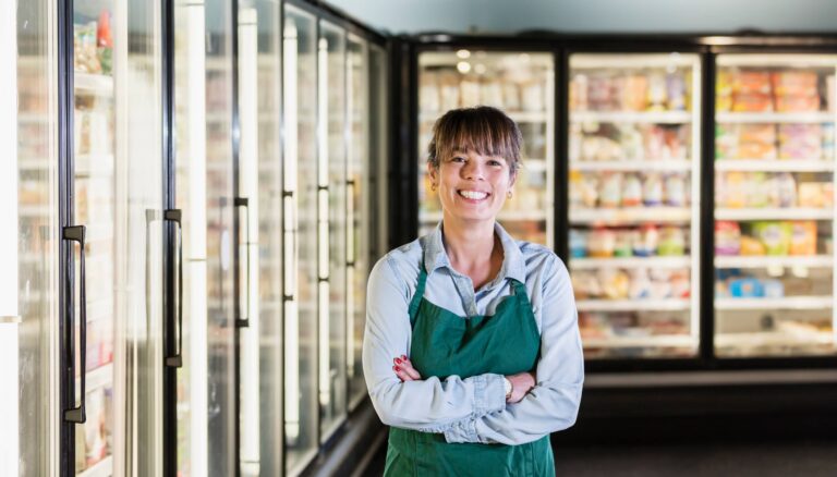 A woman standing with an apron on in a grocery store