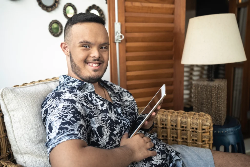 A young man smiling, holding a tablet
