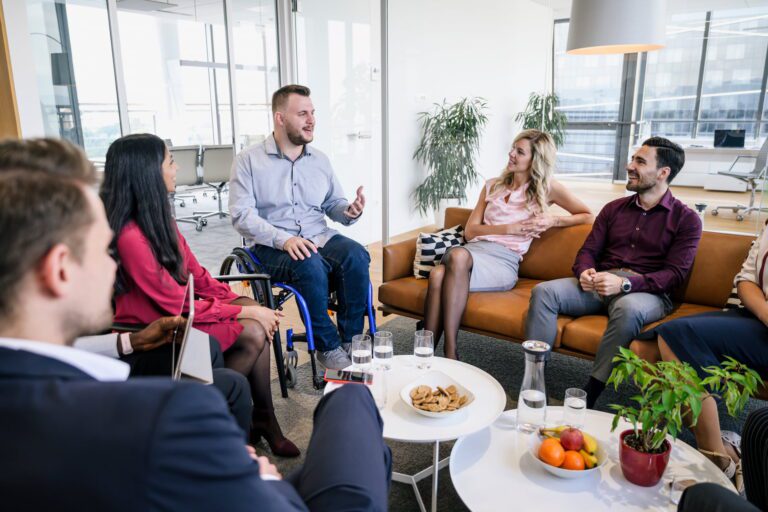 A man in a wheelchair speaking to work colleagues in a casual setting