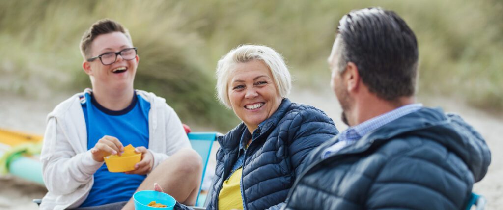 Parents with teenage child sitting, laughing at the beach