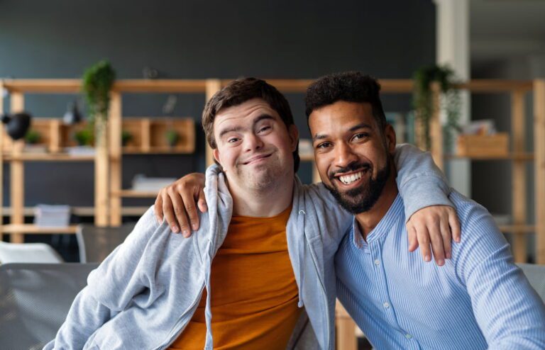 A young man with his arm around his support worker, both smiling