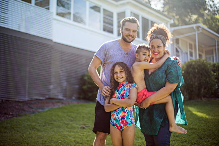 Mum, dad, young son and daughter standing in front of their home