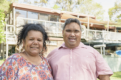 Two adults in front of their house smiling