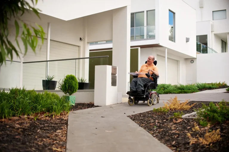Man in wheelchair in front of a house.