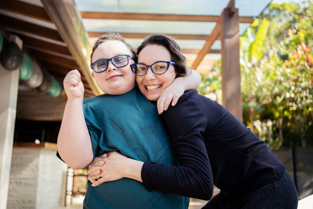 A mum hugs her son, school aged both smiling