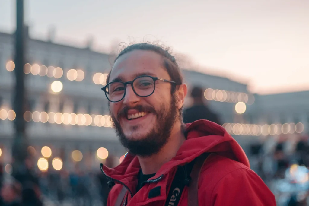 man with glasses and a red jacket outside smiling at the camera