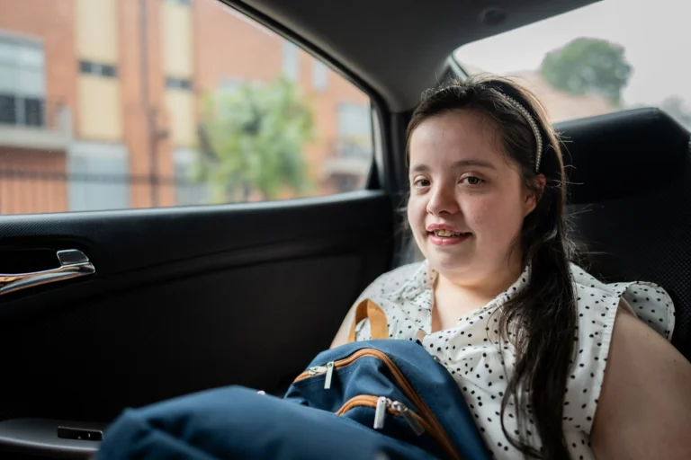 Young woman smiling while sitting in the back seat of a taxi.