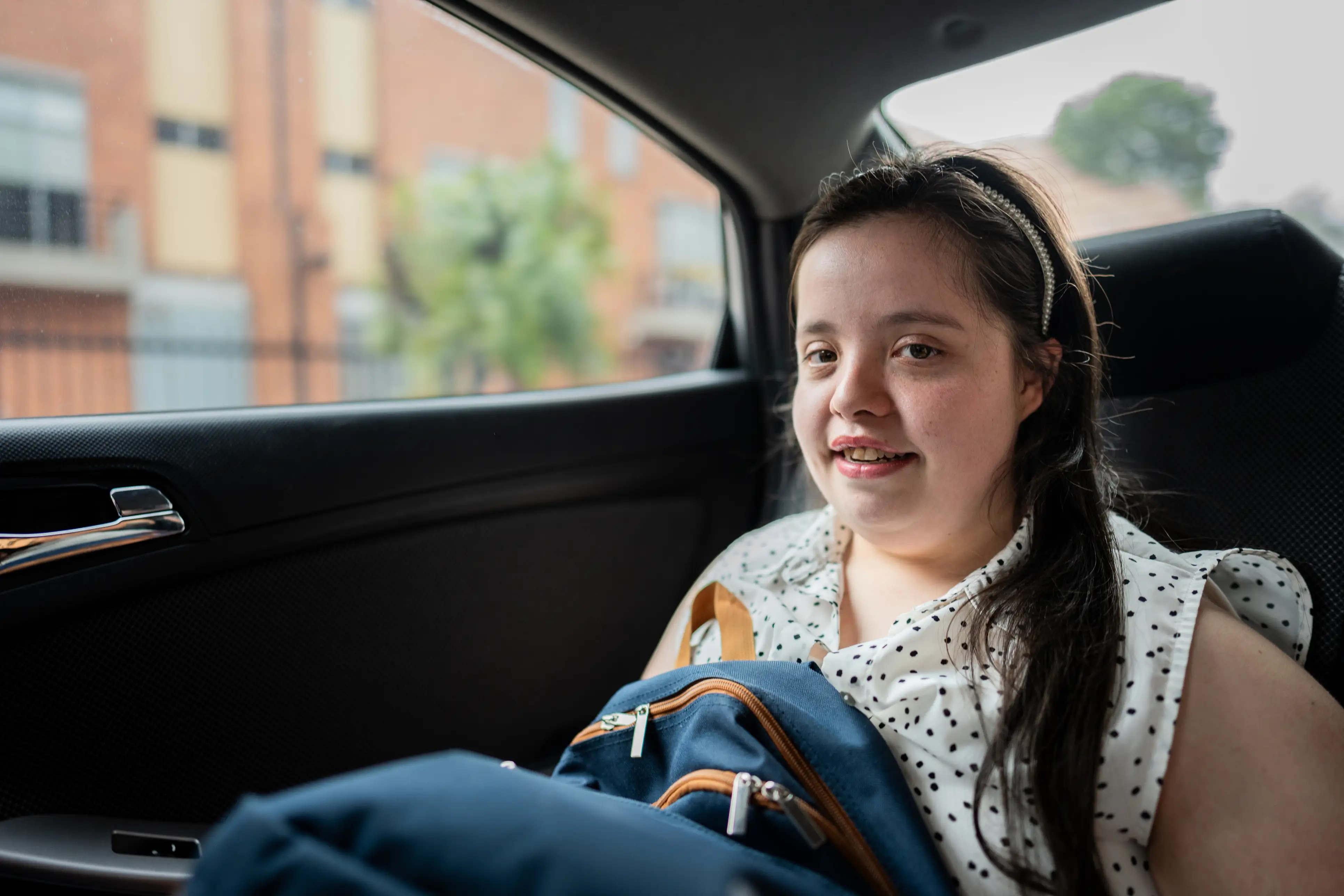 Young woman smiling while sitting in the back seat of a taxi