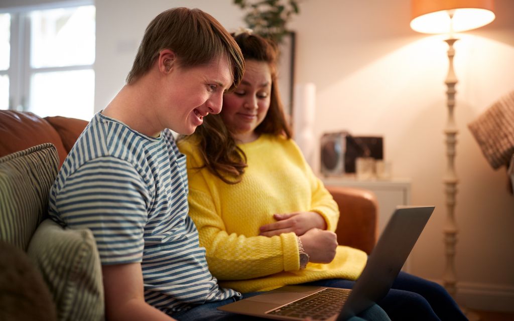 Two young adults sitting on a lounge looking at a laptop