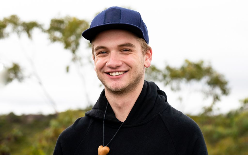 Young man wearing a baseball cap and smiling at the camera