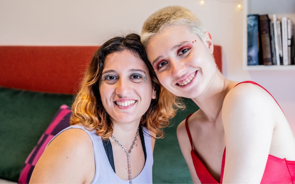 Two girls sitting on a lounge smiling at the camera