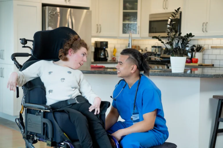 Nurse assisting young woman in wheelchair in home
