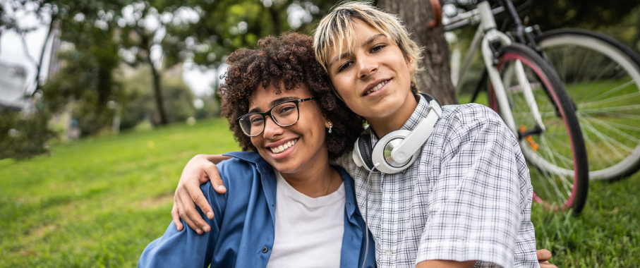 Two young adults smiling with their arms around each other