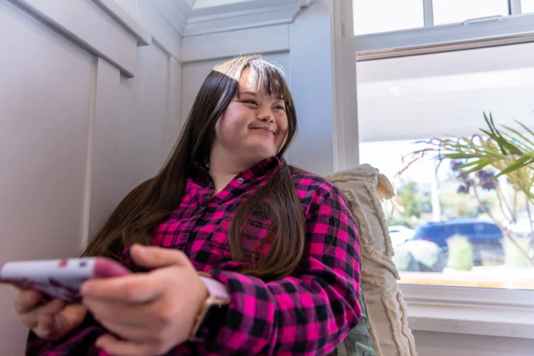 Young woman sitting by the window using smartphone.