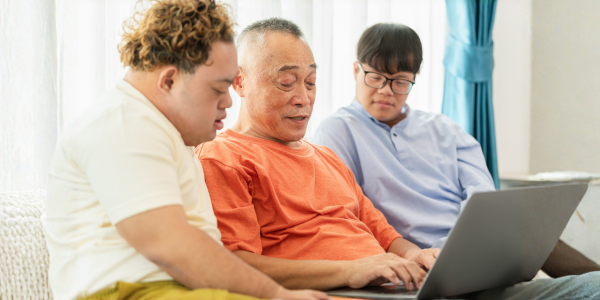 Grandfather and grandson using laptop doing a video call in living room,