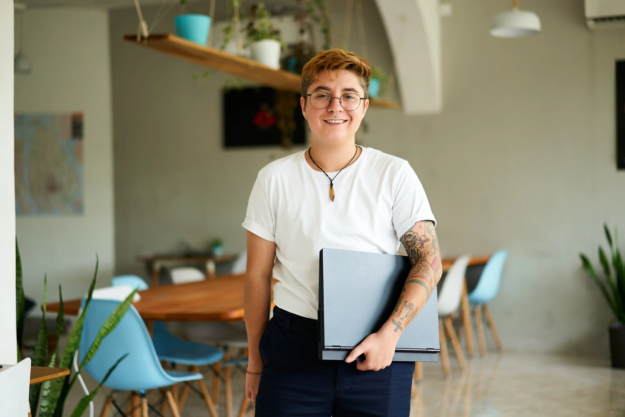 Young person holding laptop and smiling.