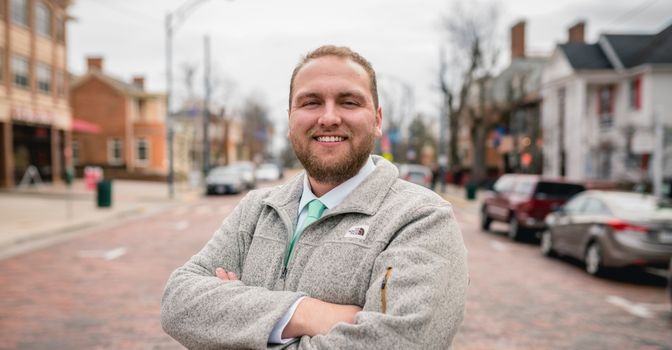 A man is standing outside and smiling