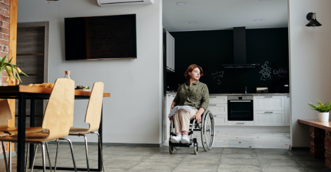 A lady in a wheelchair is in her kitchen in her accessible home.